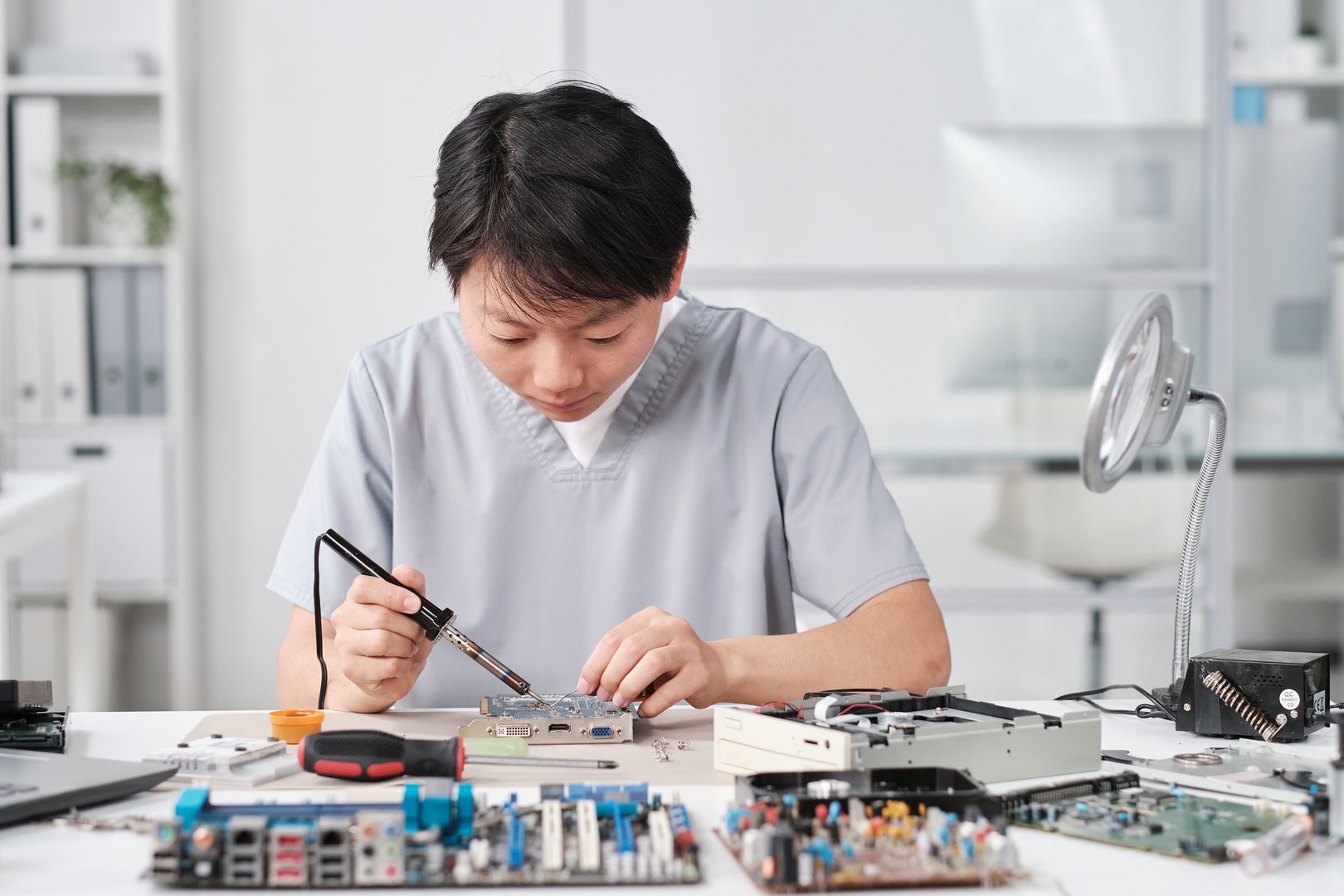 Young Chinese female technician in uniform repairing circuit board