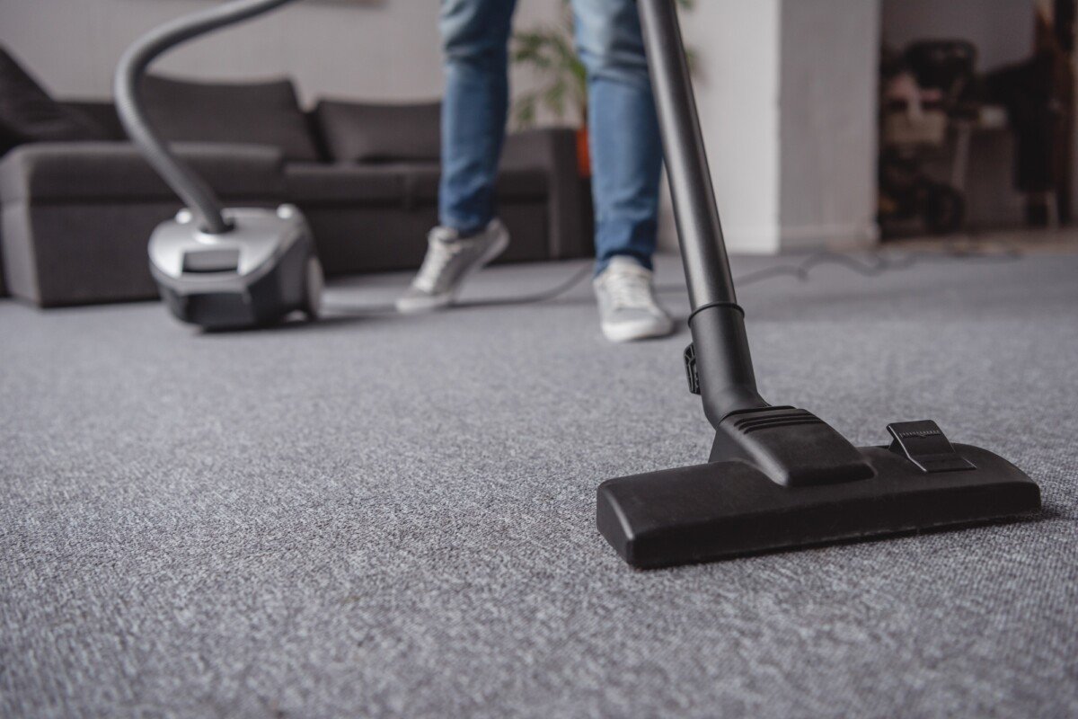 cropped image of man cleaning carpet in living room with vacuum cleaner