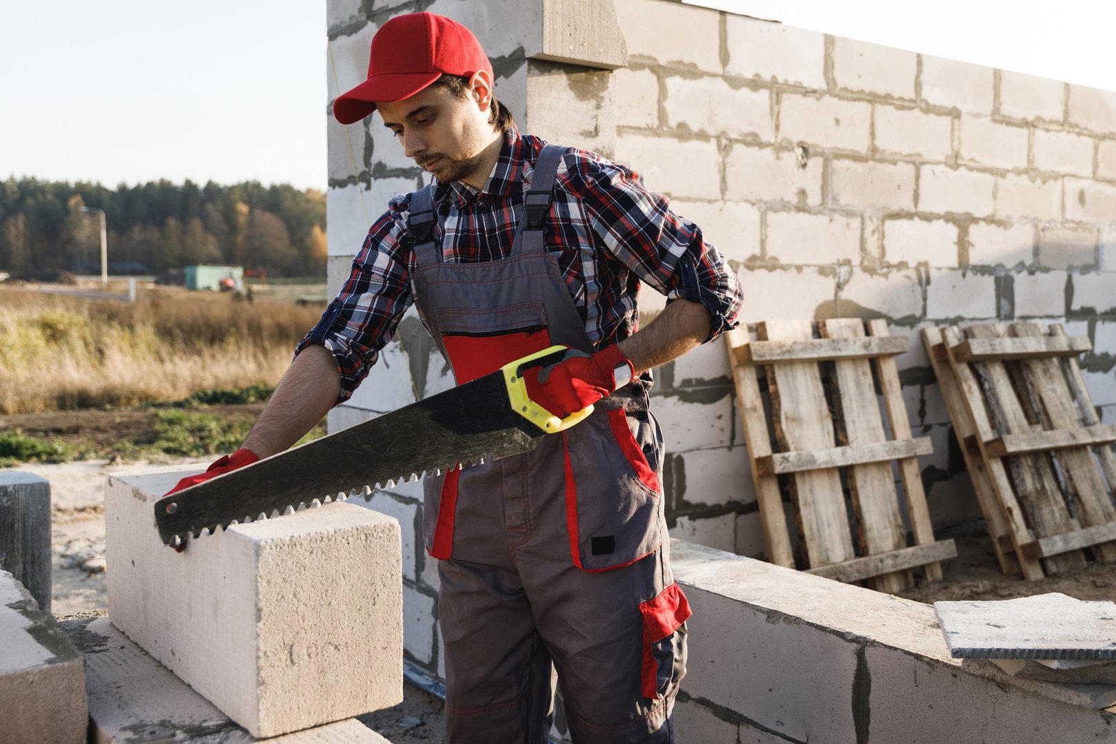 Bricklayer man is sawing autoclaved concrete blocks