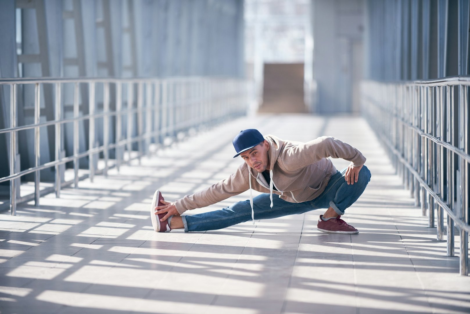 Young man practices yoga asana indoors in the empty covered footbridge