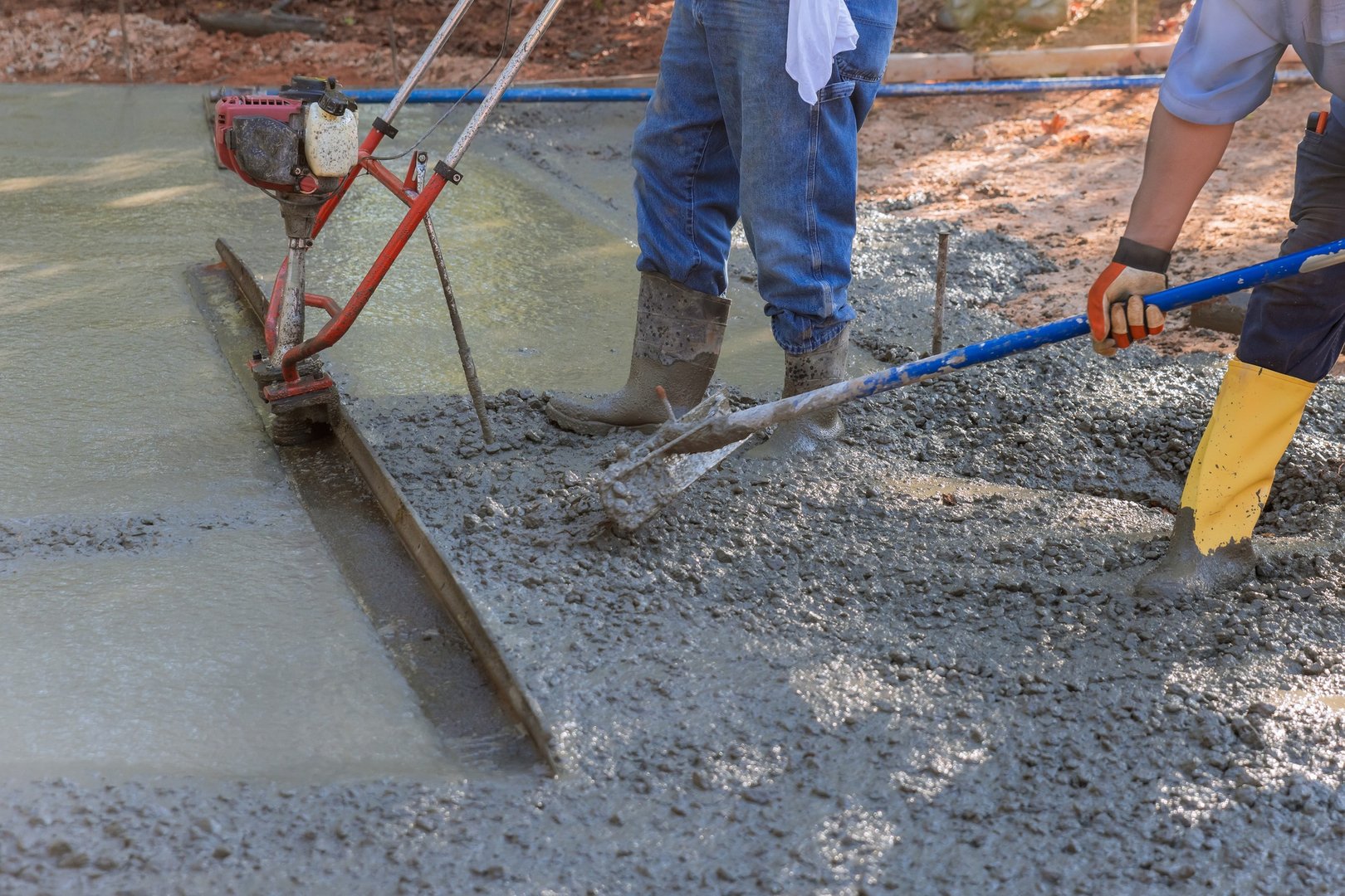 In the construction of a new driveway, a machine is used to align fresh concrete on top of the
