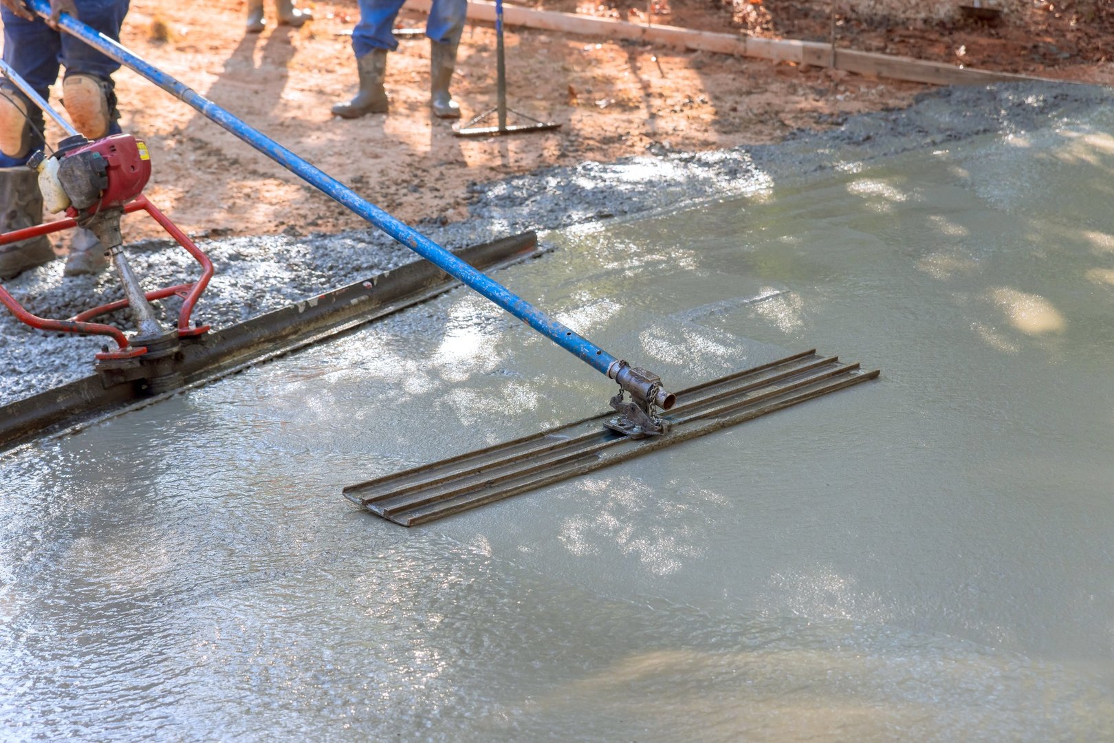 In addition to leveling concrete for driveways, workers use a trowel to level