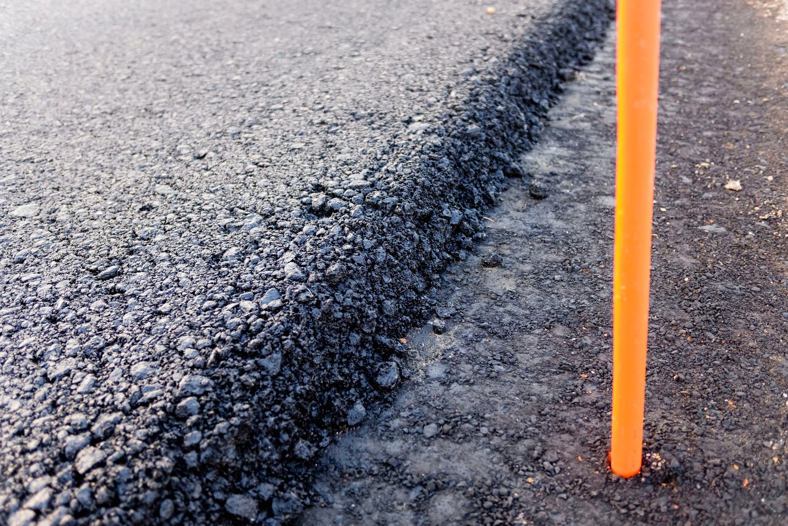 Detail of the edge of a freshly paved road with marking sticks.
