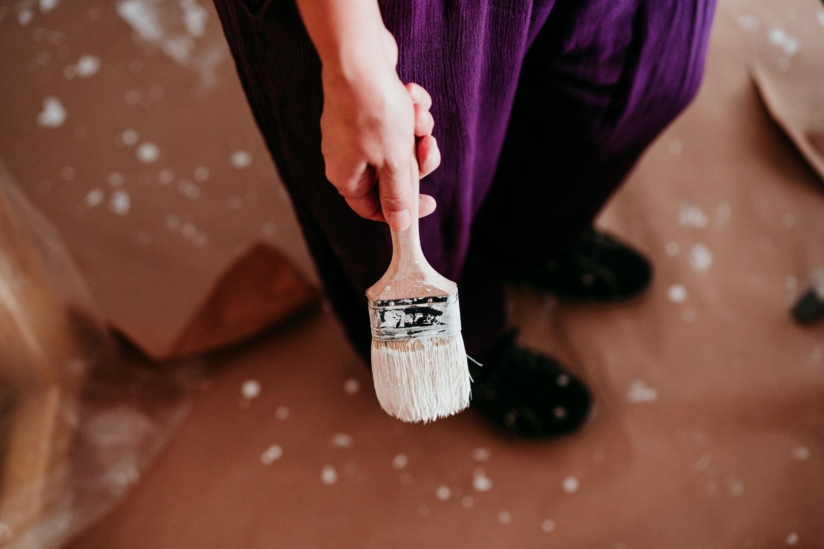 woman holding painting brush for improvement painting walls with white color. Do it yourself