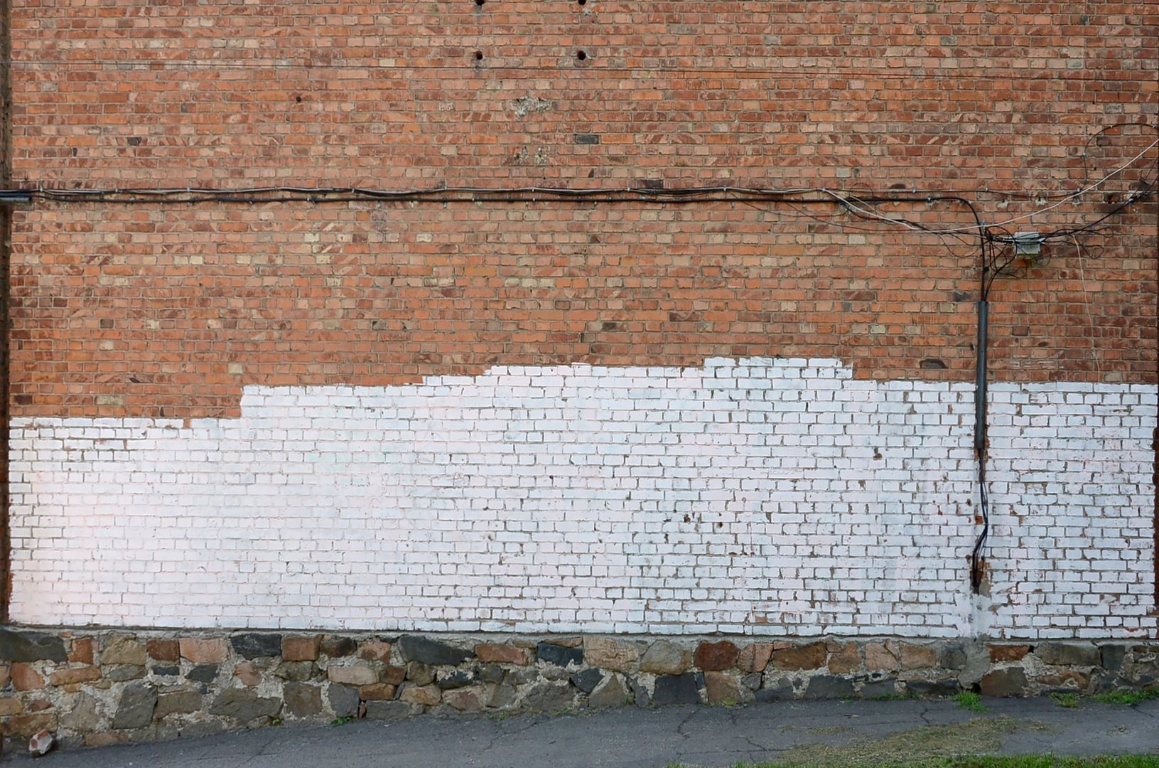 Residental house wall with white paint patches covering graffiti vandalism on exterior