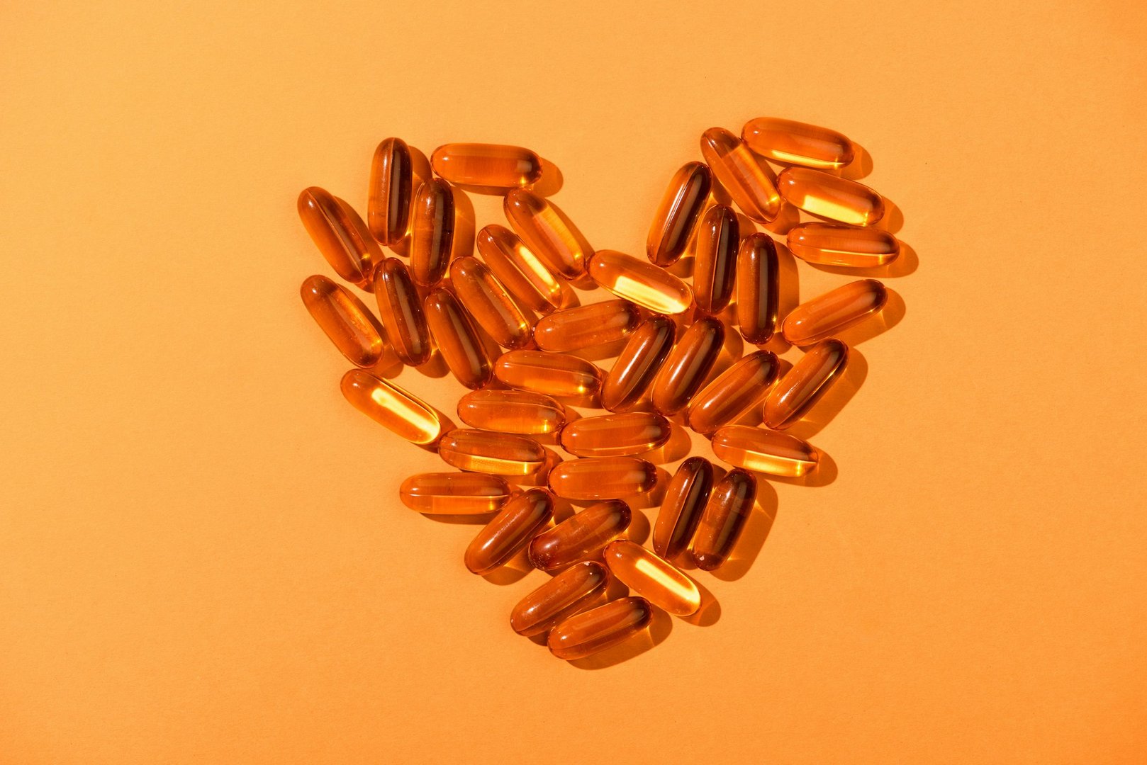 Top View of Decorative Heart From Fish Oil Capsules on Orange Background