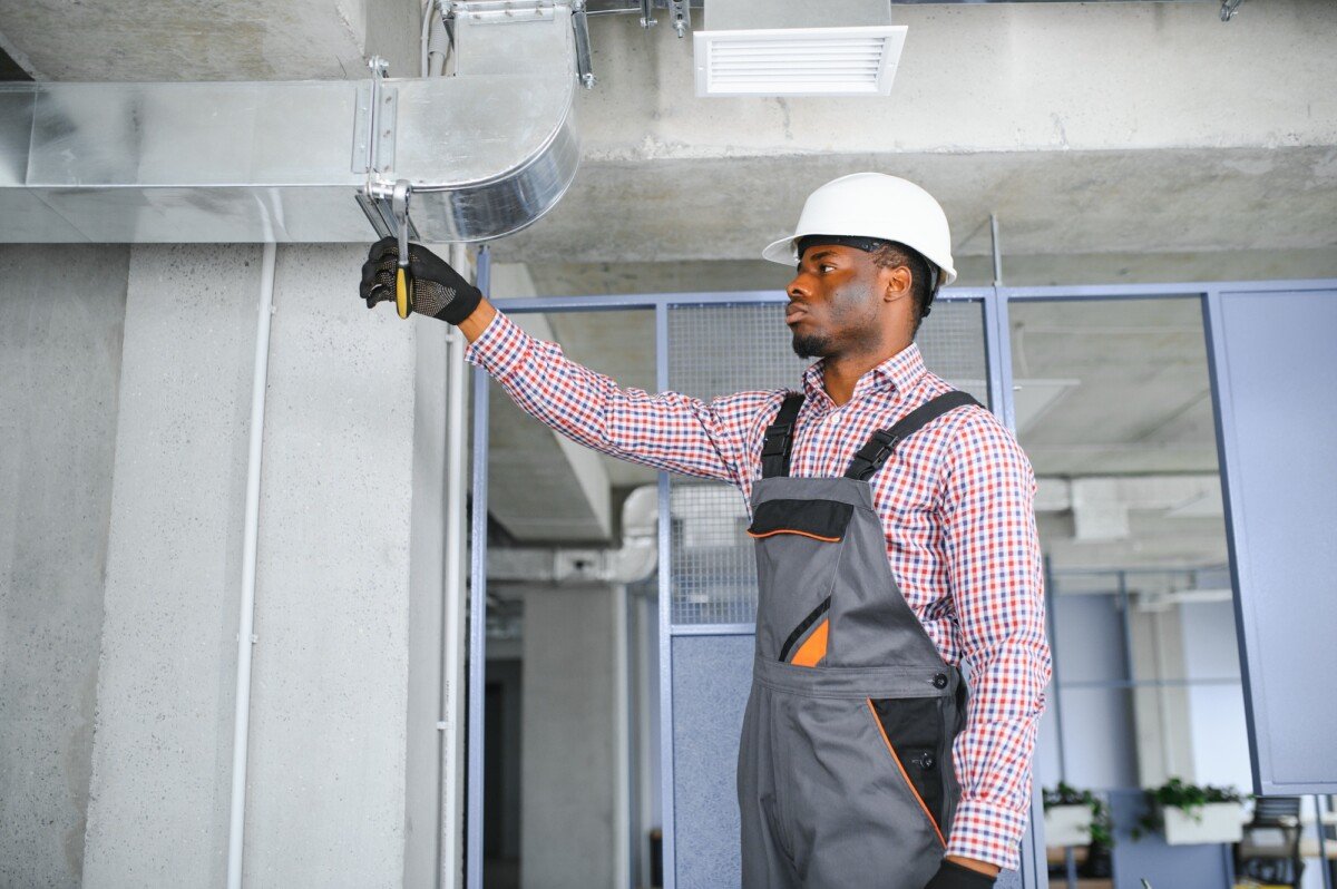 hvac african worker install ducted pipe system for ventilation and air conditioning. copy space