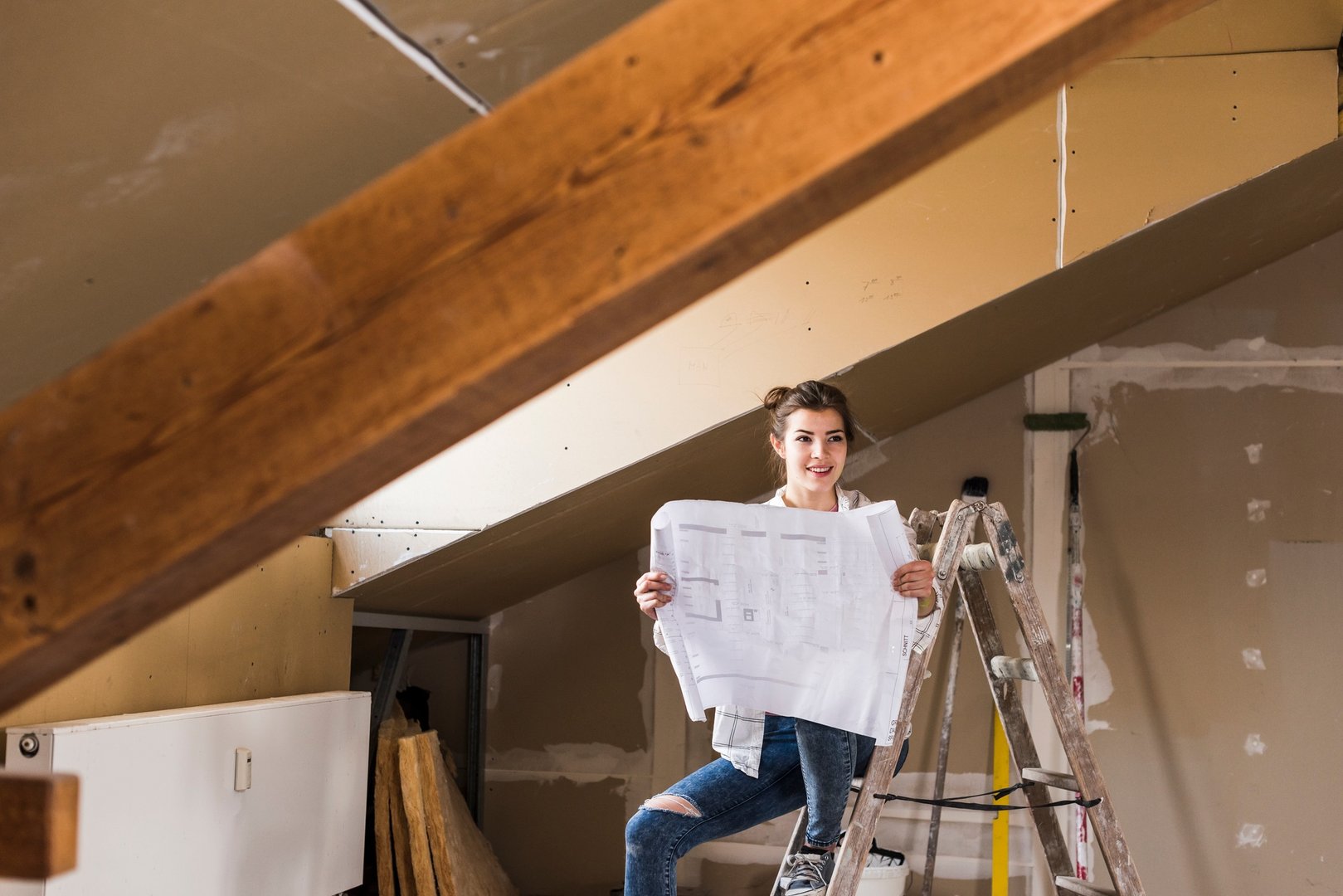 Young woman renovating her new home, holding construction plan