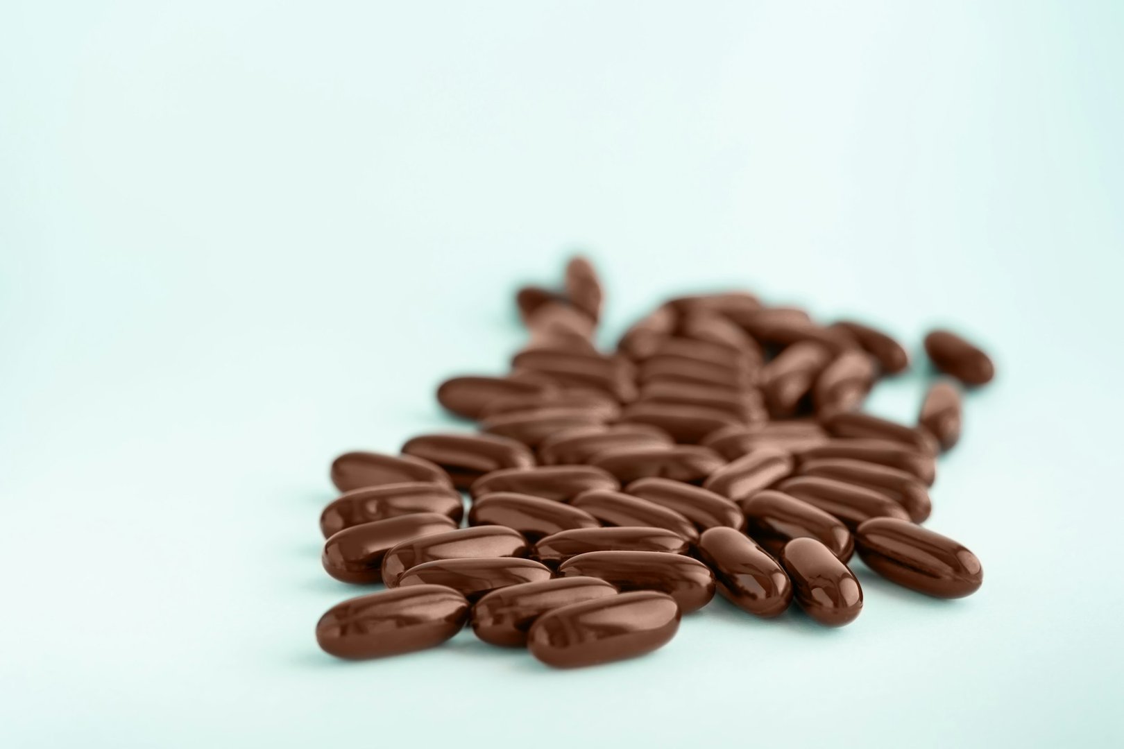 Brown capsules, gel pills with oil isolated on blue background. Nutritional supplements for weight