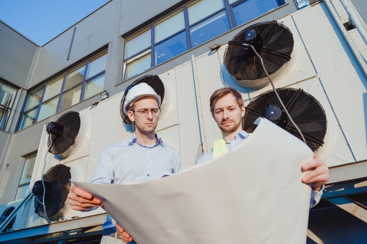 Service hvac engineer and internship in uniform with paper drawings at industrial fridge machine