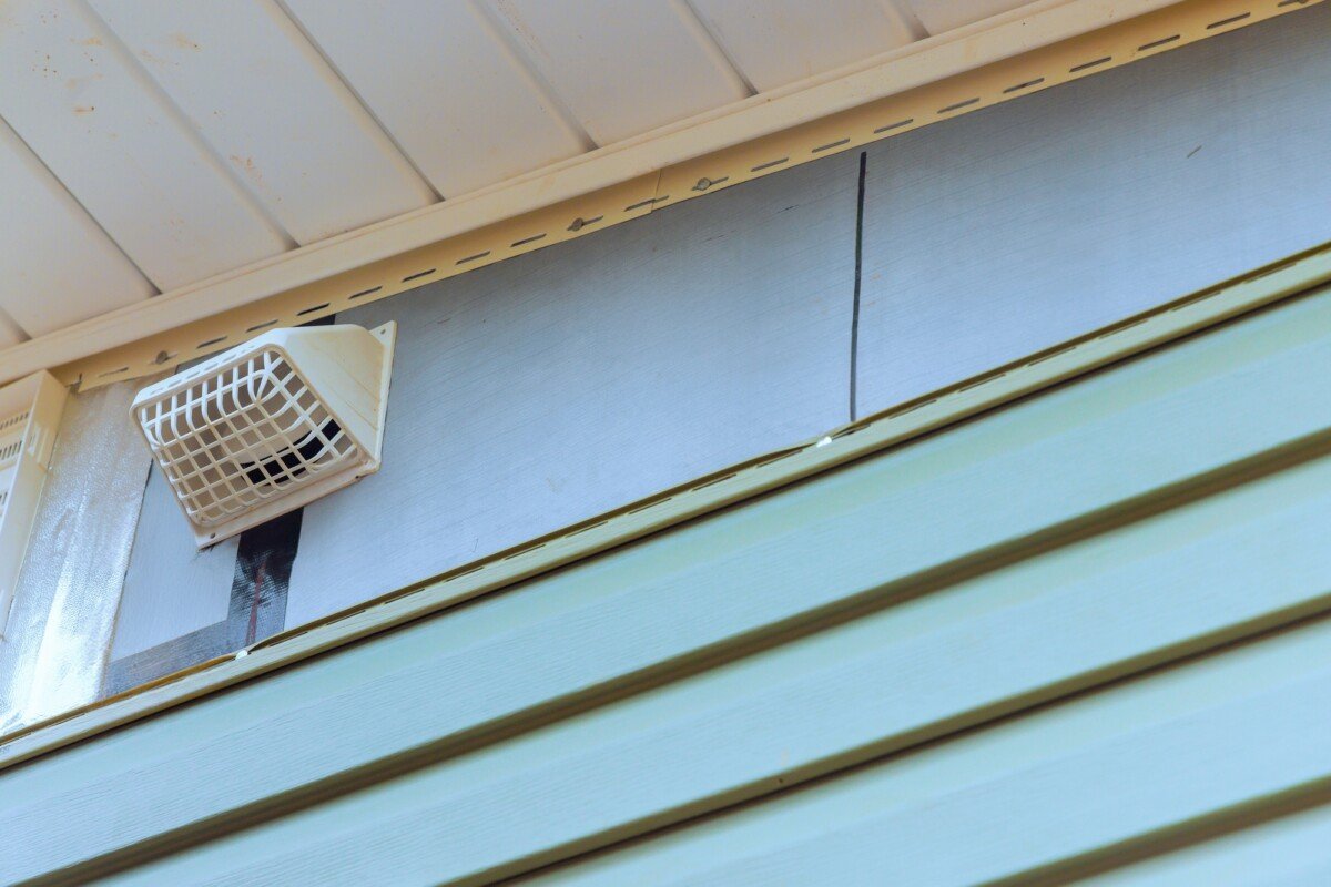 Installing vinyl siding plastic panels on facade wall of new home by an a employee