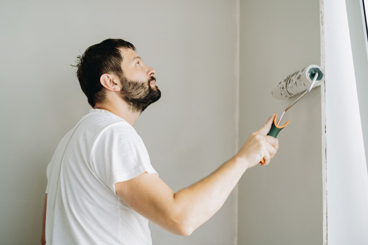 caucasian bearded man painting wall with paint roller. Painting apartment, renovating home