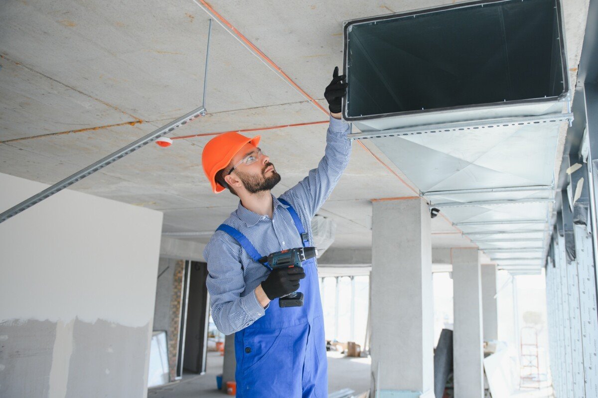 Warehouse Heating and Cooling System Installation by Professional Caucasian Technician.