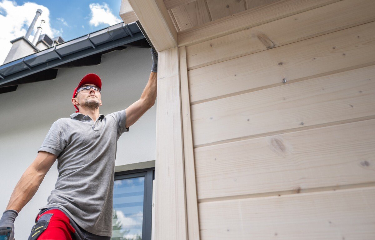 Worker Performing Maintenance on the Exterior of a House During a Sunny Afternoon