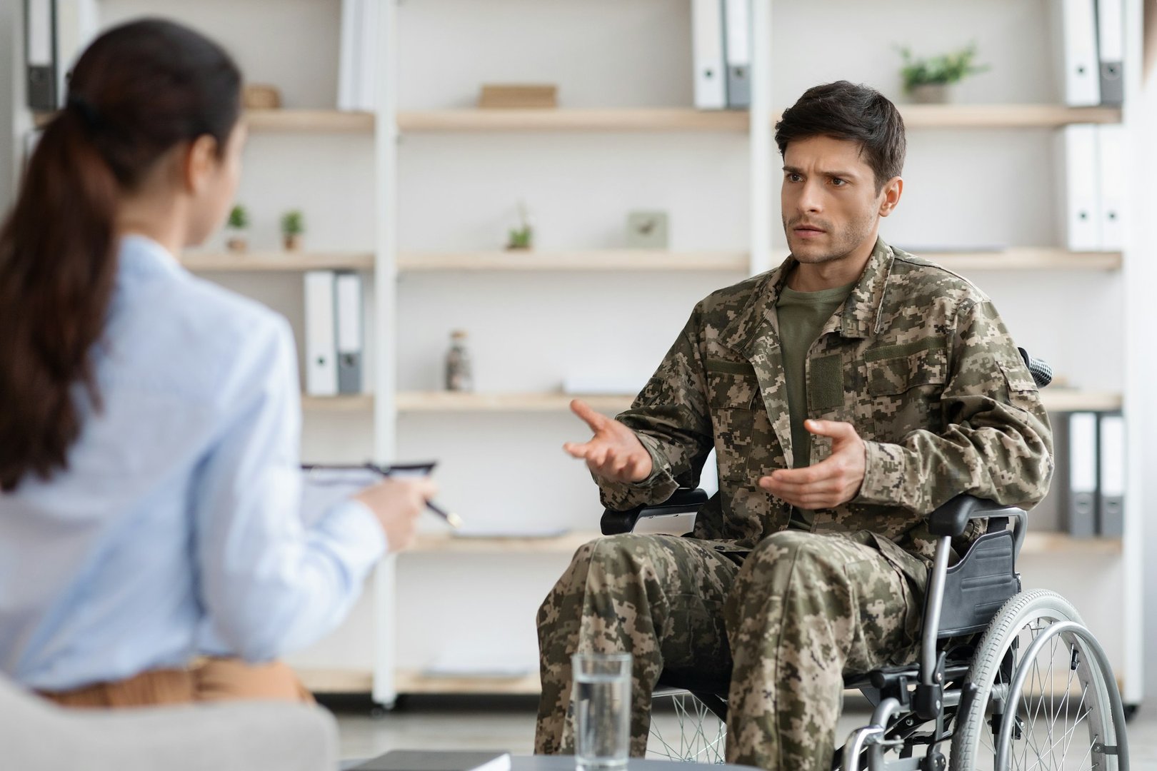 Unhappy disabled young man military veteran attending female psychologist