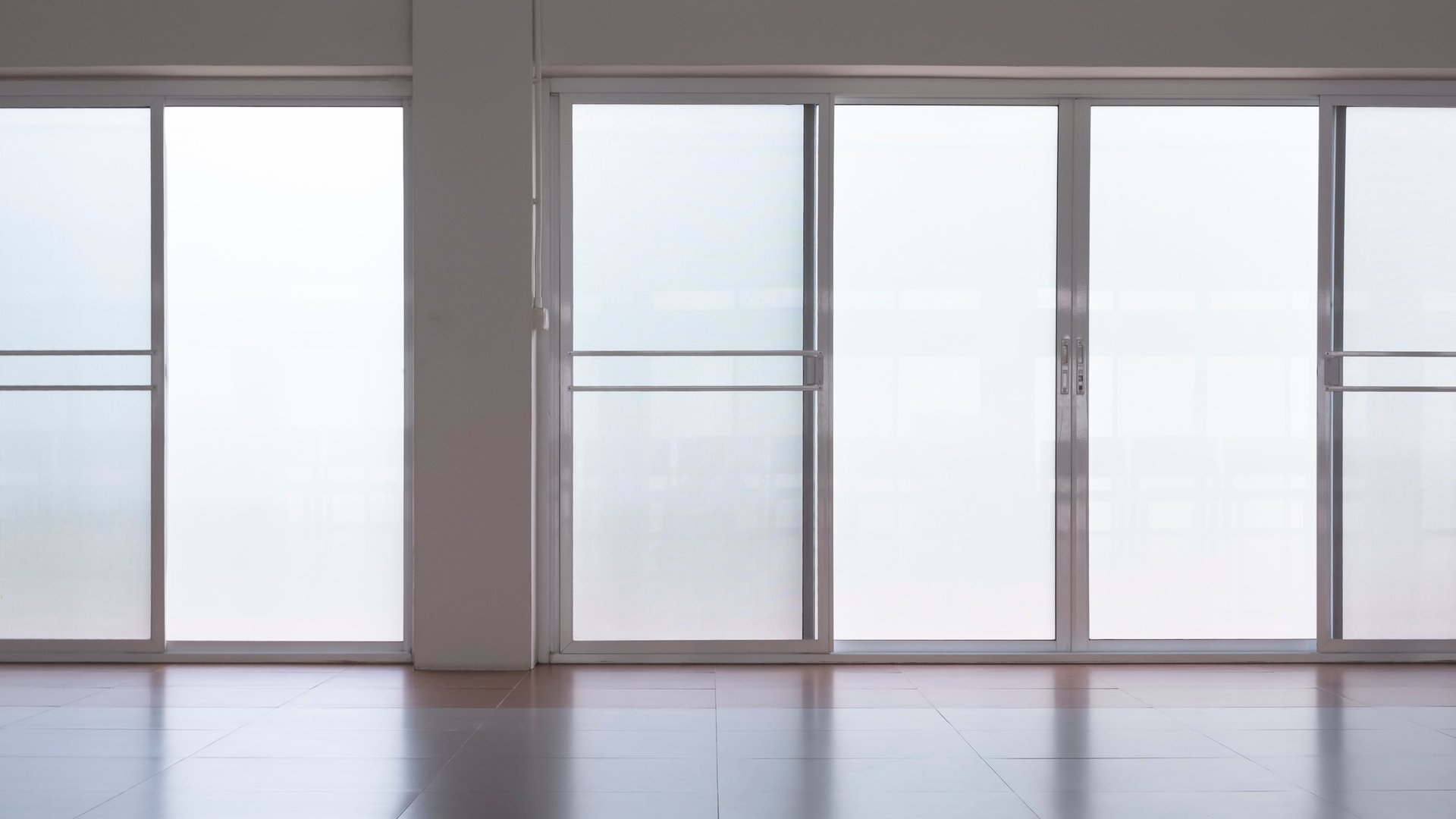 frosted glass sliding doors with screen doors and light reflection on tile floor in empty room