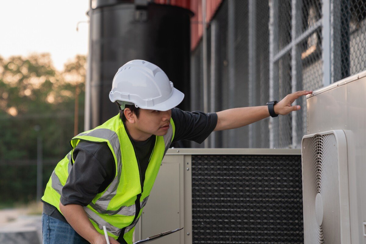 Engineers are inspecting the cooling system of an air conditioning unit in industrial facility.