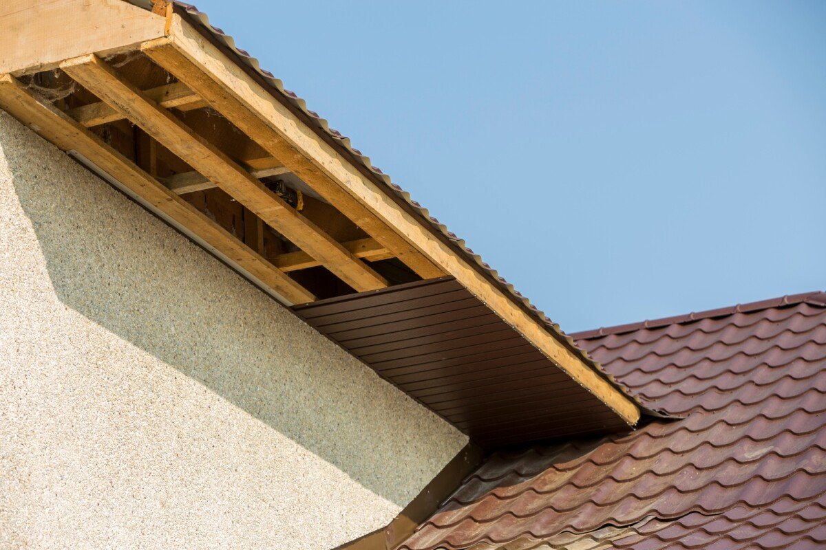 Bottom view detail of new modern house cottage corner with stucco walls, brown shingled roof and