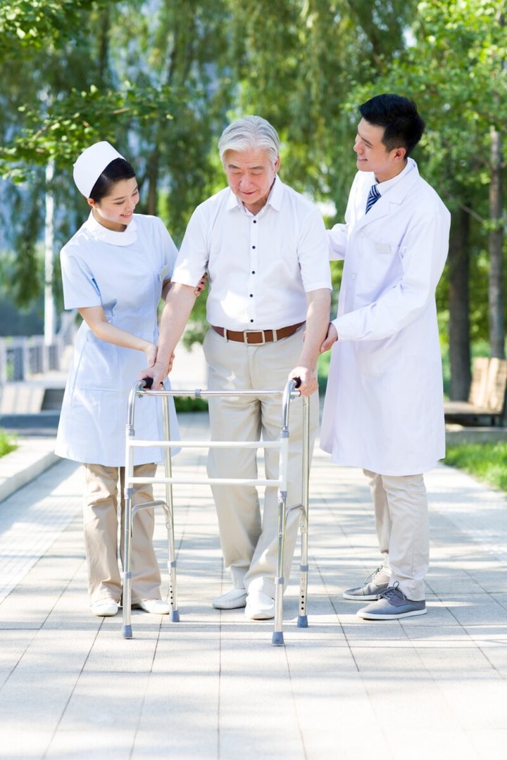Senior man walking with walking frame under doctor and nurse's assistance