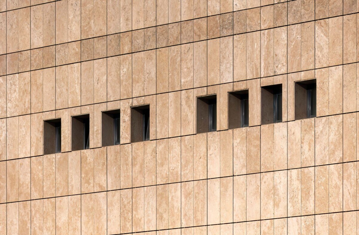 Small windows with beige brick siding on an exterior wall of a building.