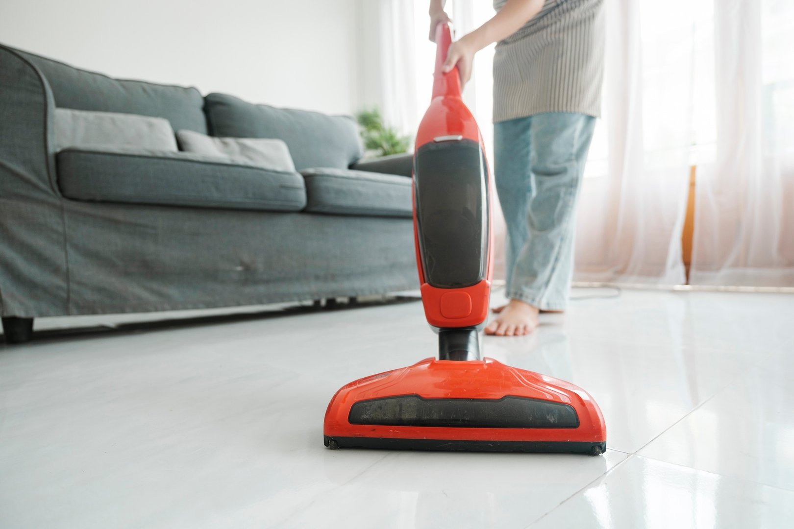 Young woman cleaning house with vacuum cleaner.
