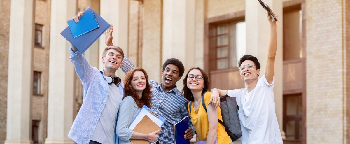 Portrait of excited international high school students raising hands up in the air after passing exam successfully