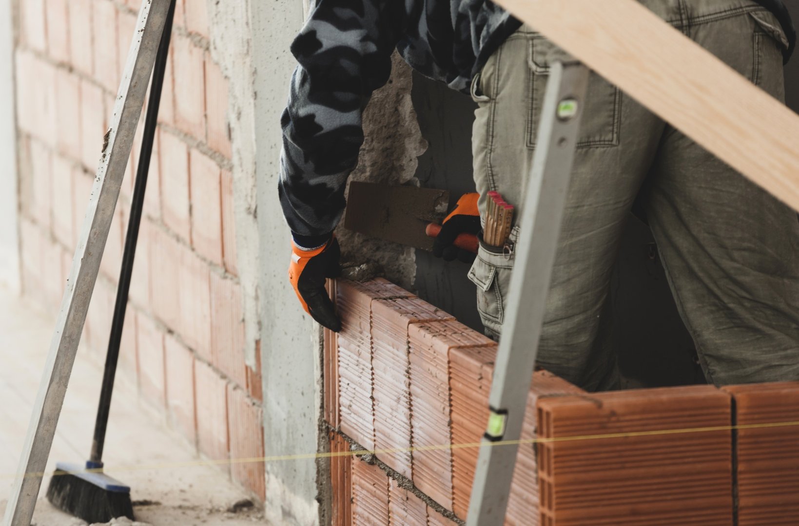 Bricklayer installing brick masonry on interior wall.