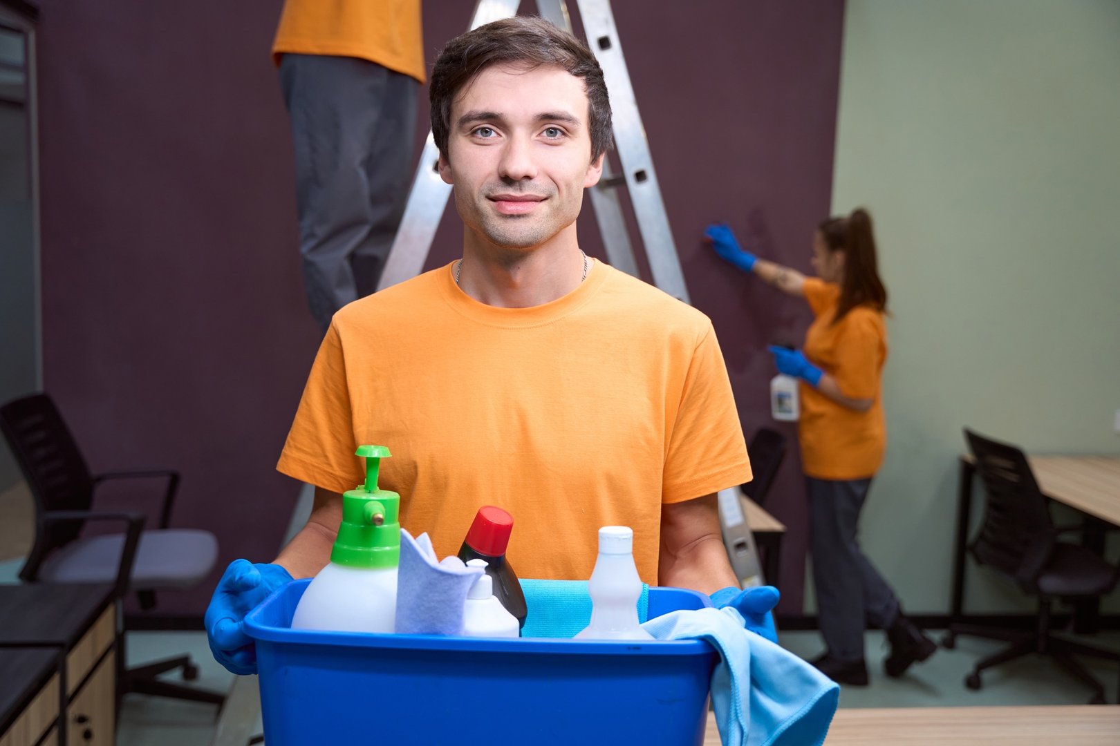 Friendly cleaning service worker smiling and holding chemicals