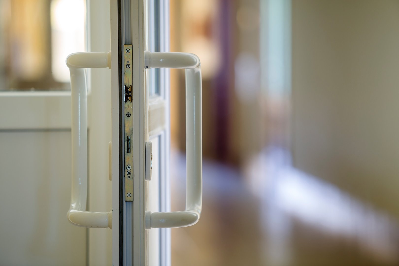 White plastic door detail with metal lock, handle and transparent glass