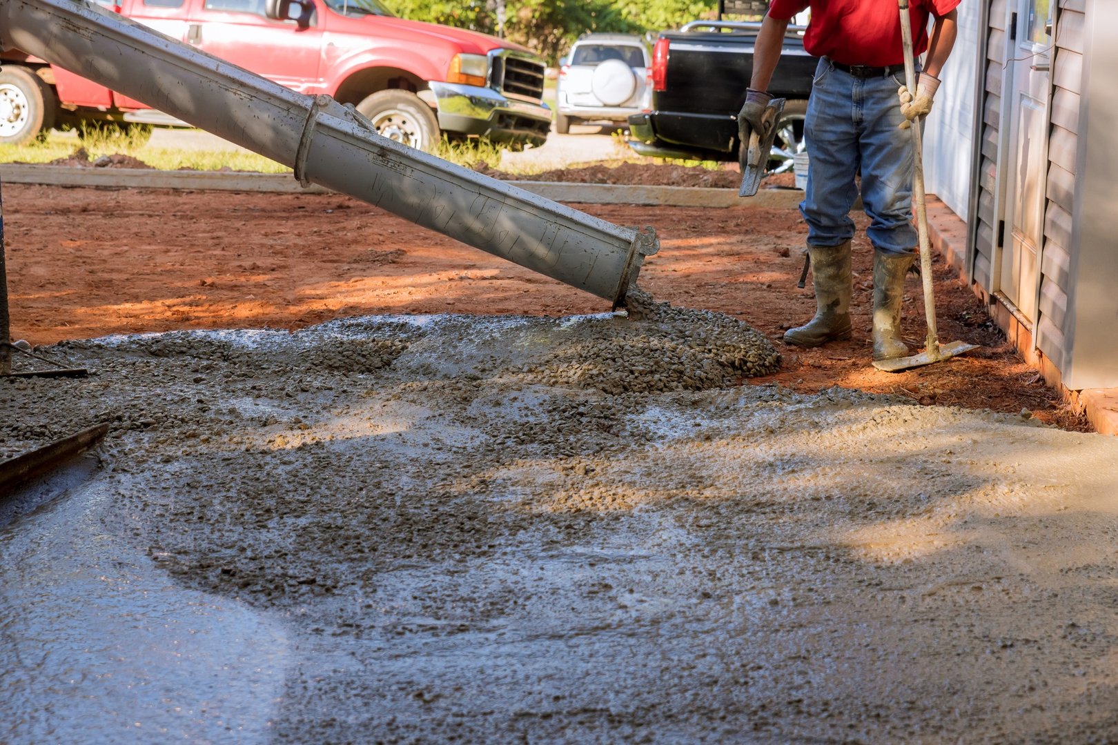 Concrete construction contractors working on a pouring wet concrete while paving a driveway