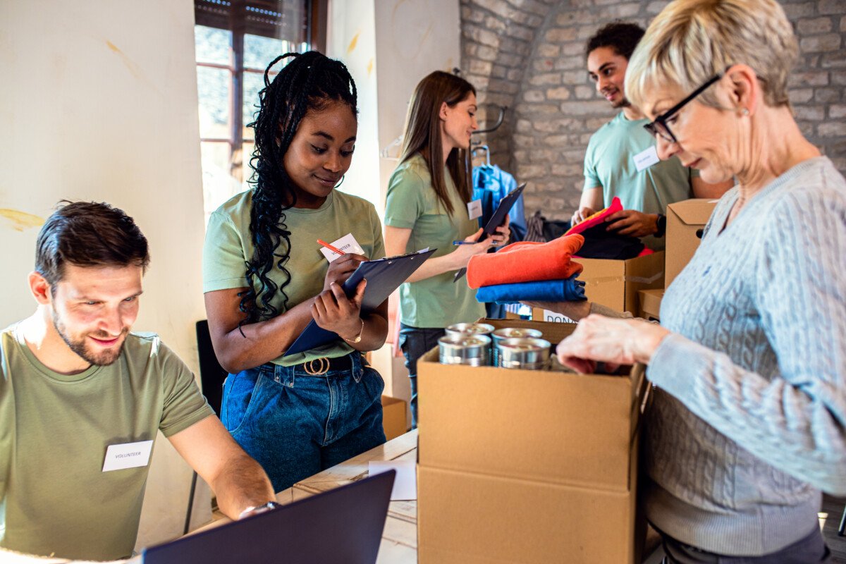 Group of volunteers with working in community charity donation center.