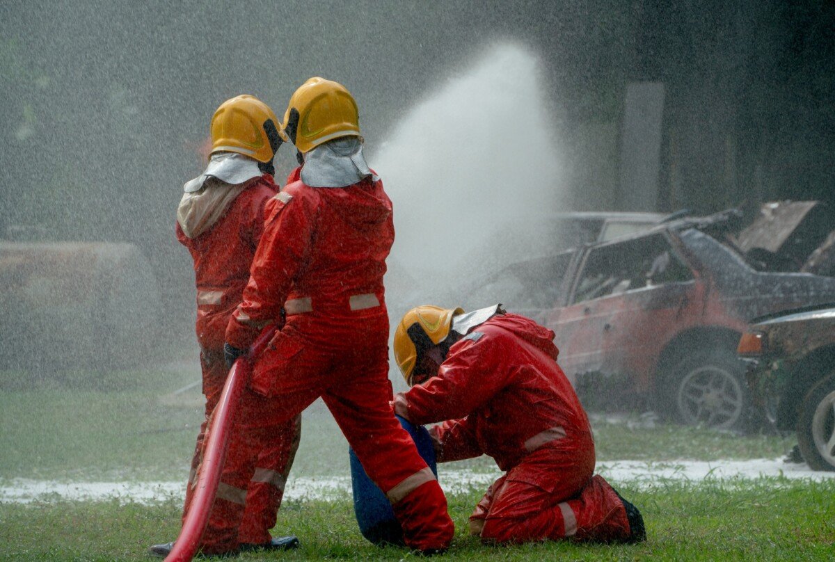 Three firefighters help and support to use fire sprinkler to spray water mix with special foam
