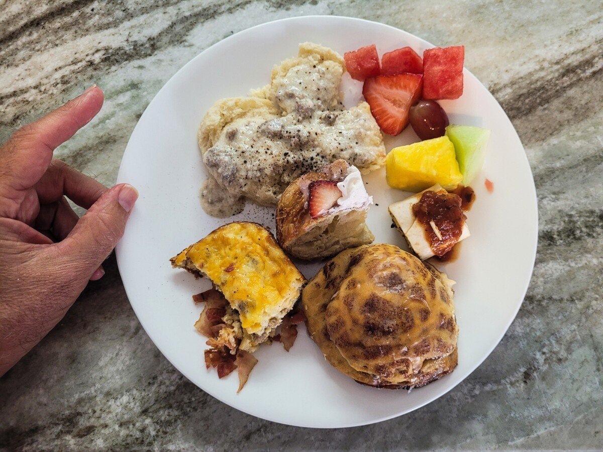 Man has plate of food ready to eat for brunch on granite countertop.
