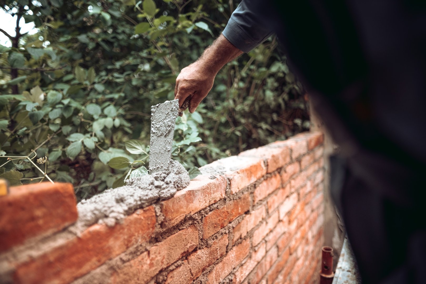 Worker placing and installing bricks on exterior wall on house construction