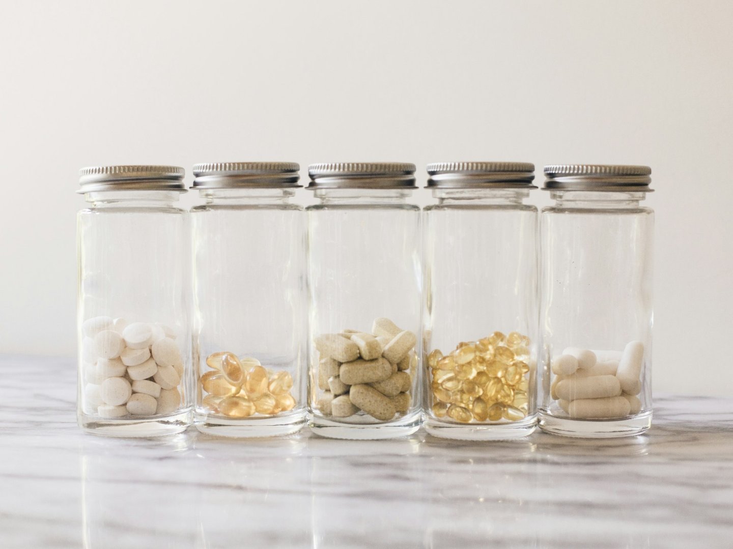 Vitamin jars hold a variety of supplements on a marble counter