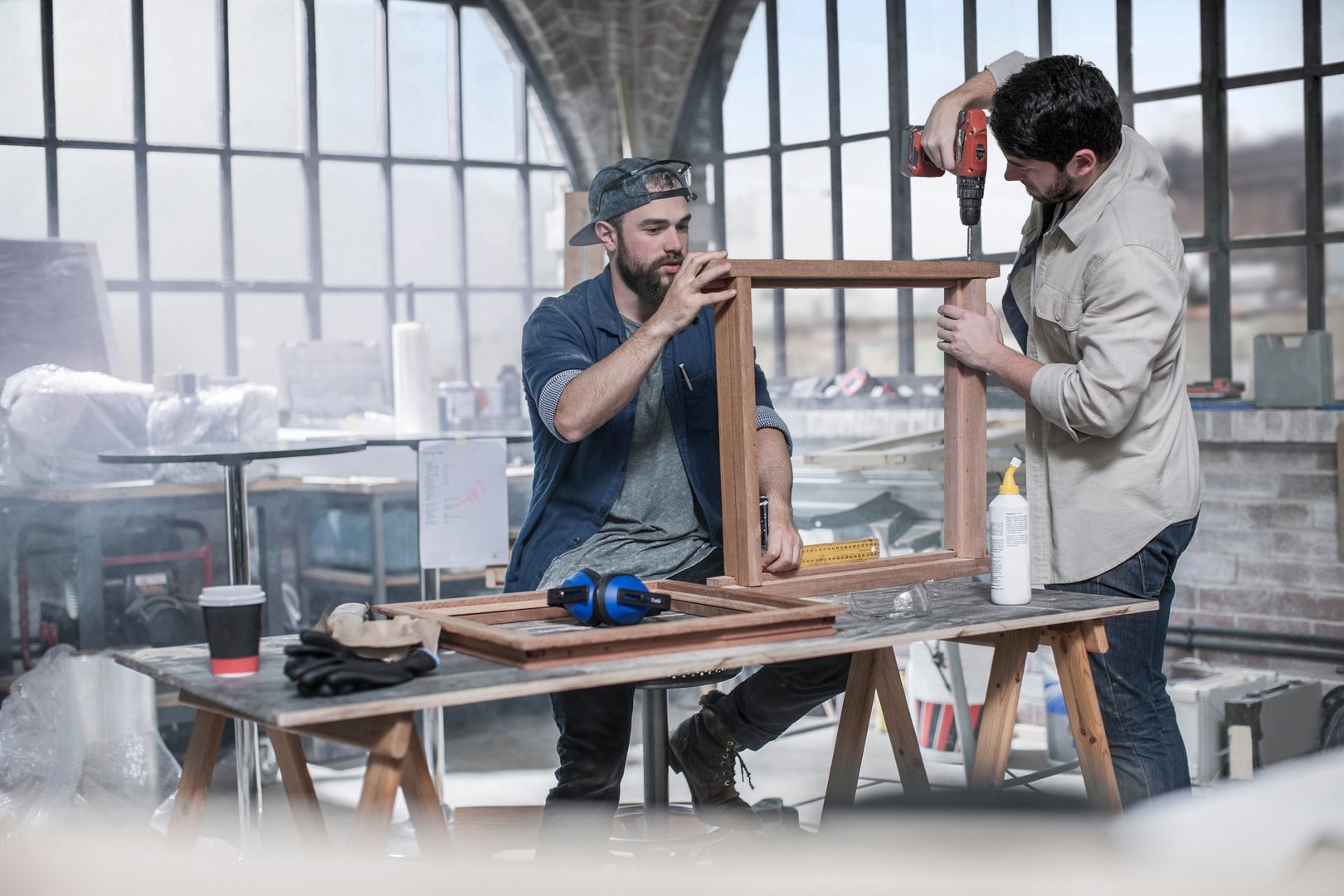 Carpenters drilling framework in antique restoration workshop