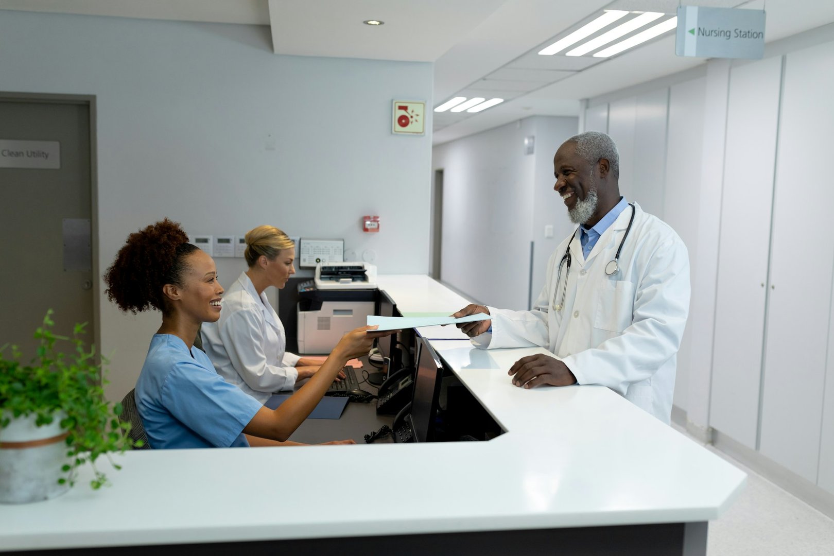 Diverse male doctors and female nurse passing medical documentation over the counter at hospital