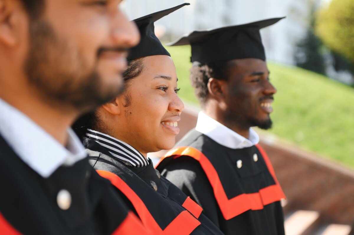 education, graduation and people concept – group of happy international students in mortar boards and bachelor gowns…