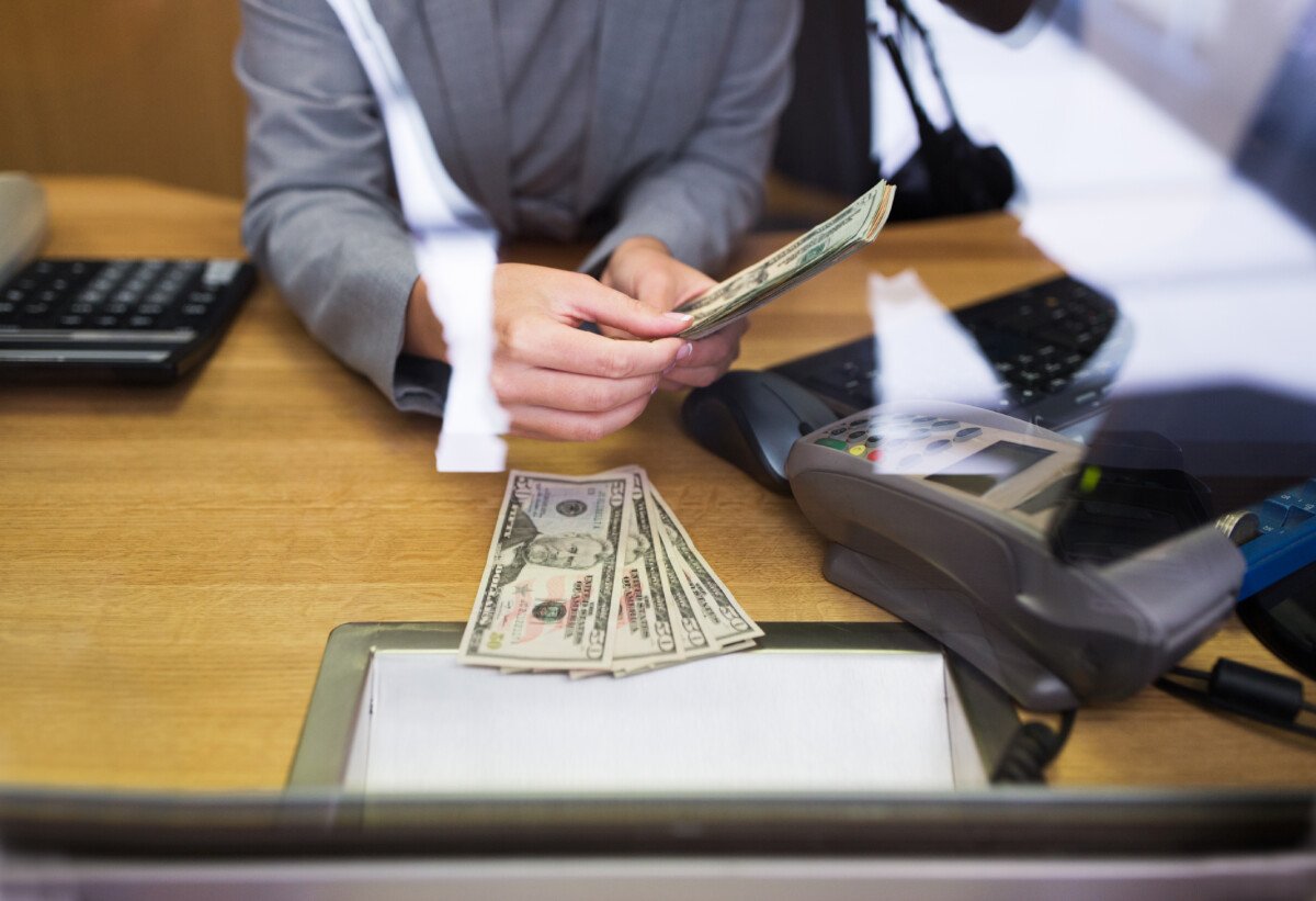 people, withdrawal, saving and finance concept – clerk giving cash money to customer at bank office or currency…