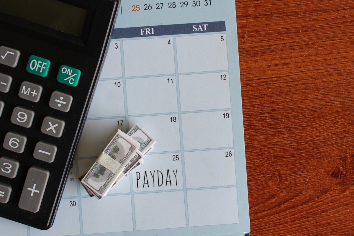 Top view image of banknotes, calculator and PAYDAY written on a calendar. Copy space for text.