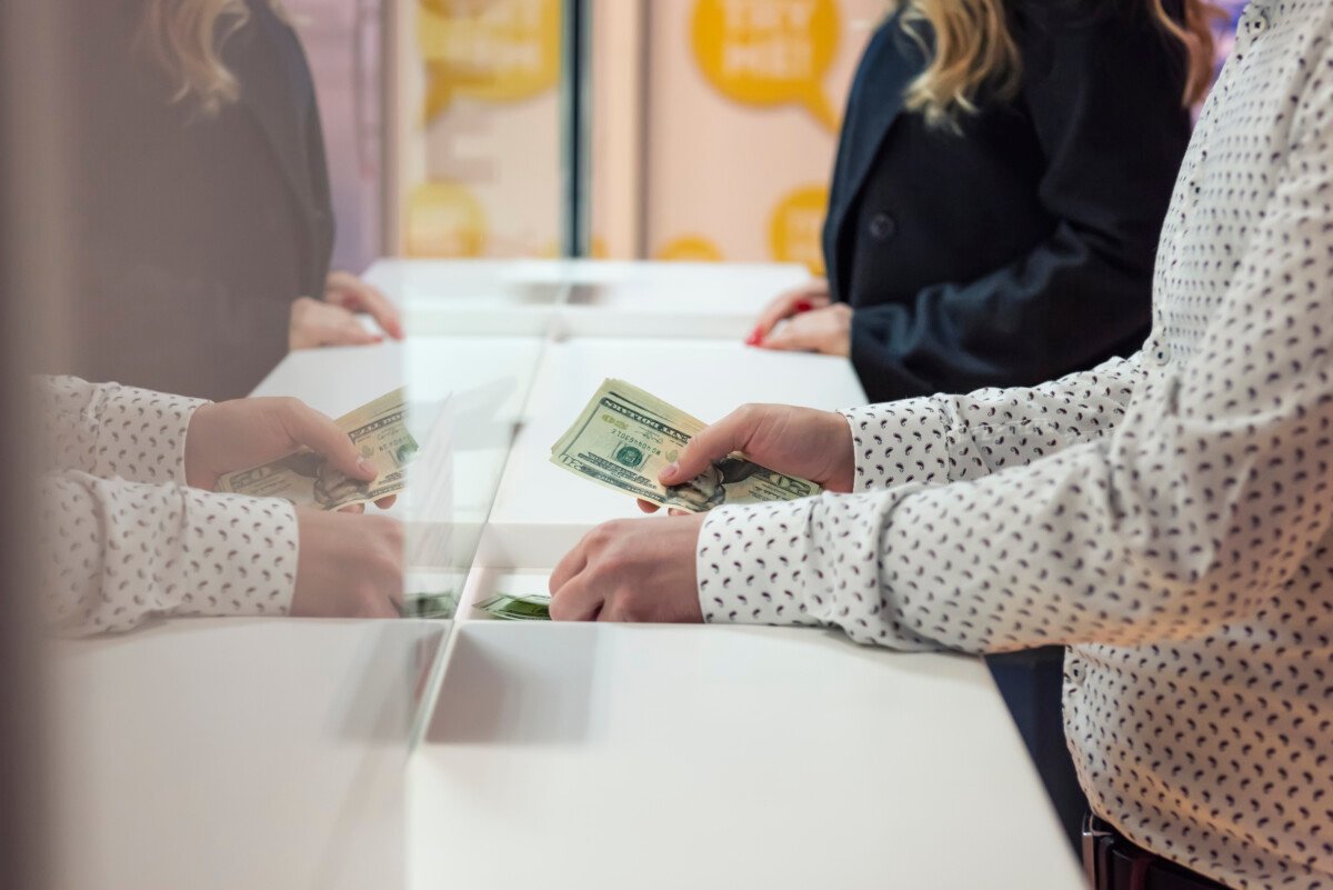 Male hand with money at cash desk. Currency exchange concept.