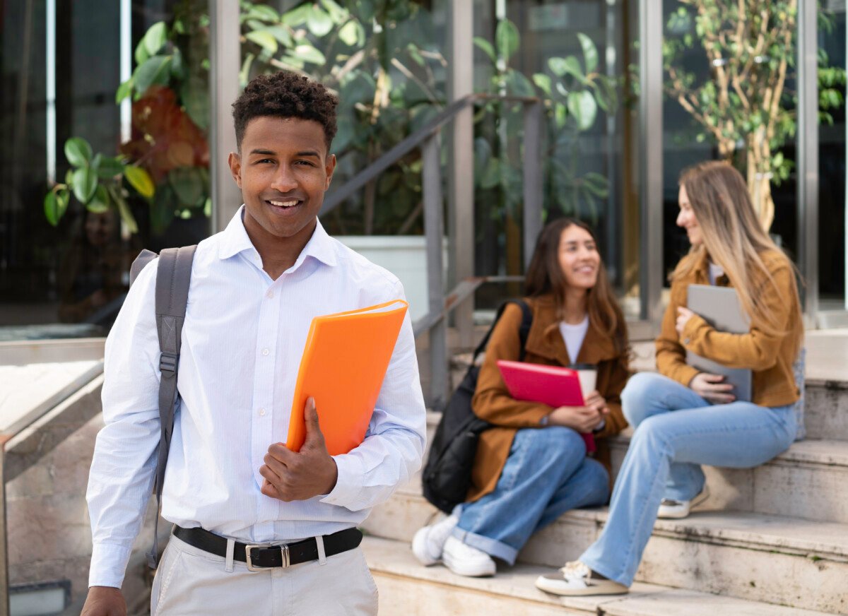 Happy african american college student standing on campus with backpack and folder, going to class.
