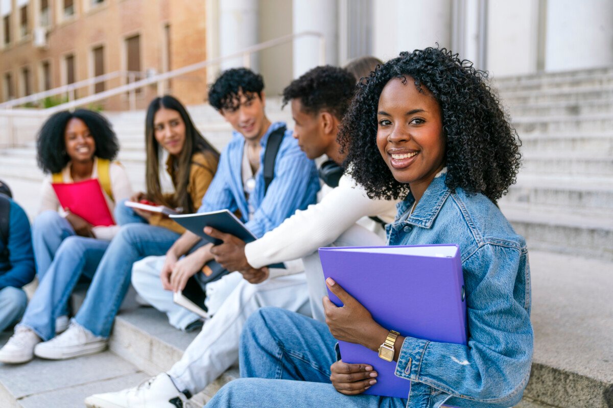 Multiracial student group relaxing and talking on campus outdoor stairs, embodying youth, friendship, and education