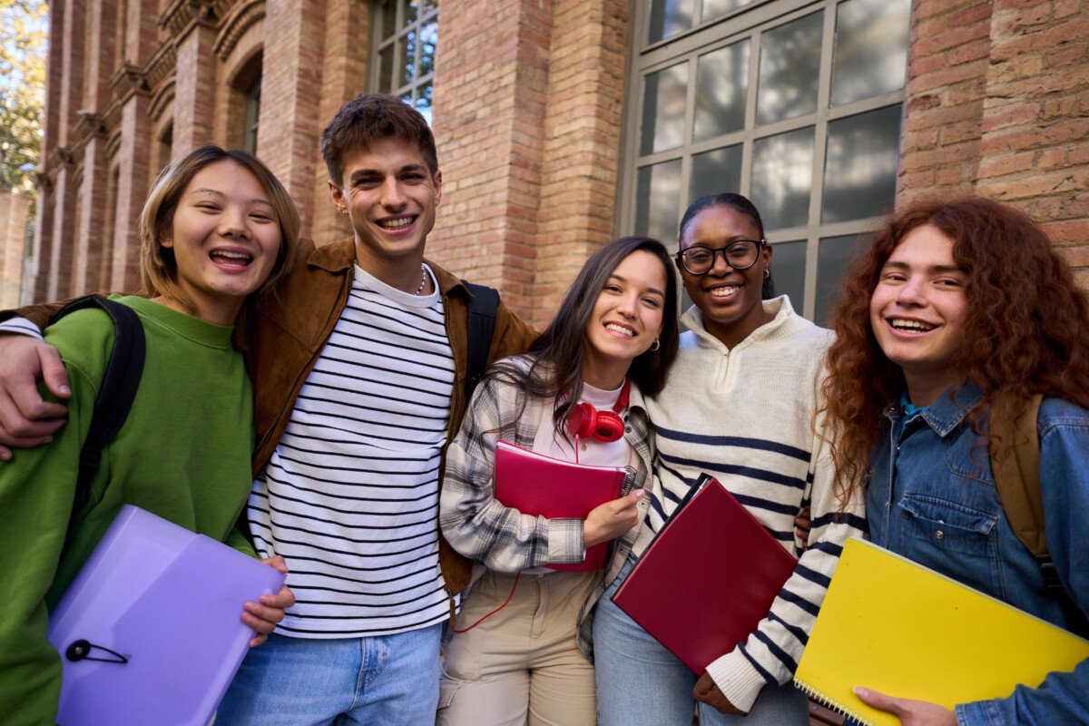 Portrait of a cheerful group of young multiracial student looking at camera having fun outside at university campus.…