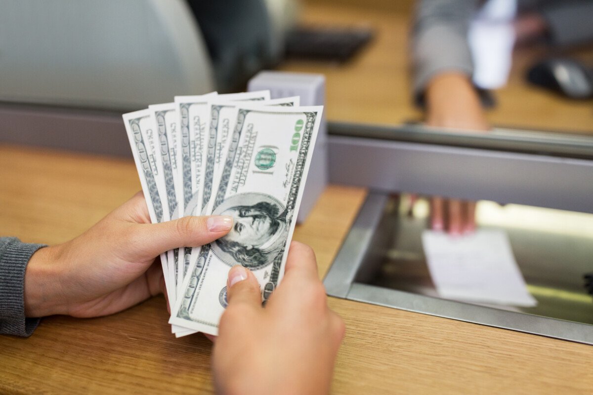 people, withdrawal, saving and finance concept – customer hands with cash money at bank office or currency exchanger