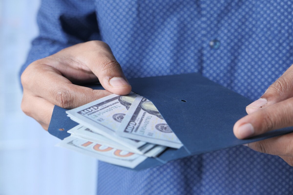 person hand putting cash in a envelope