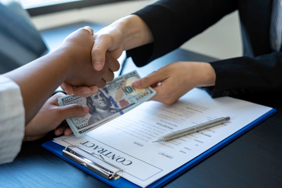 Asian businesswomen give dollars to sign home and real estate contracts and congratulate them for working together to…