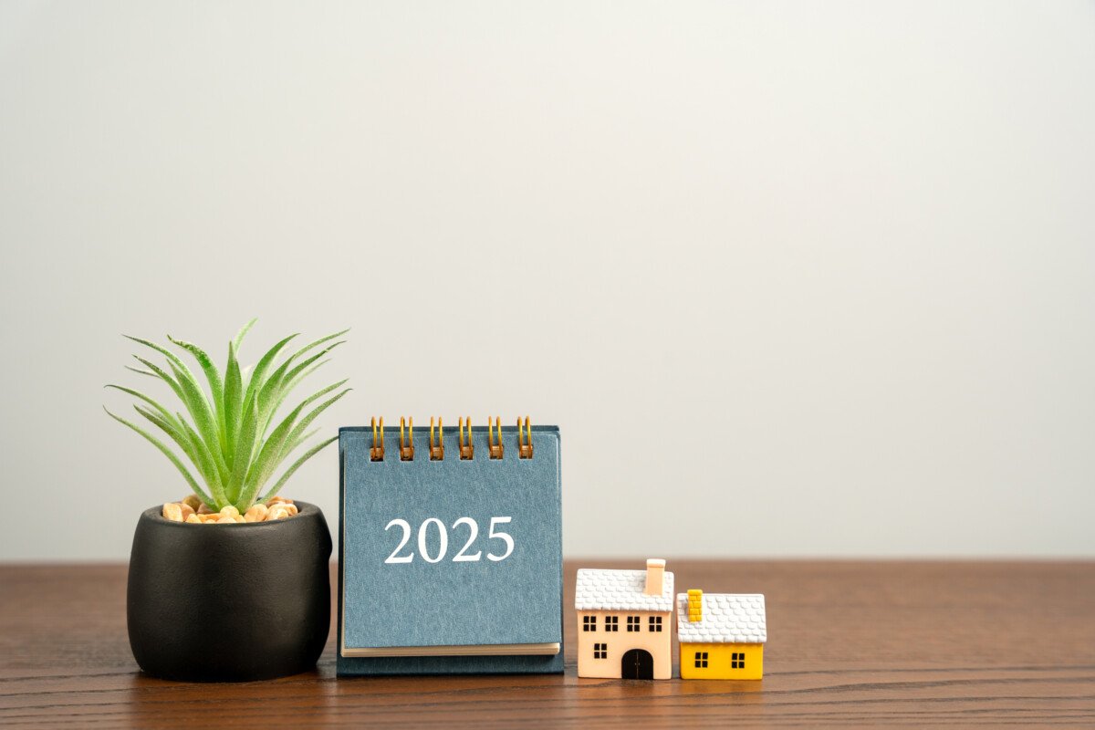 Calendar 2025, houses and succulent on a table. Beginning of a new year. Plan, planning and achieving goals. Real estate…
