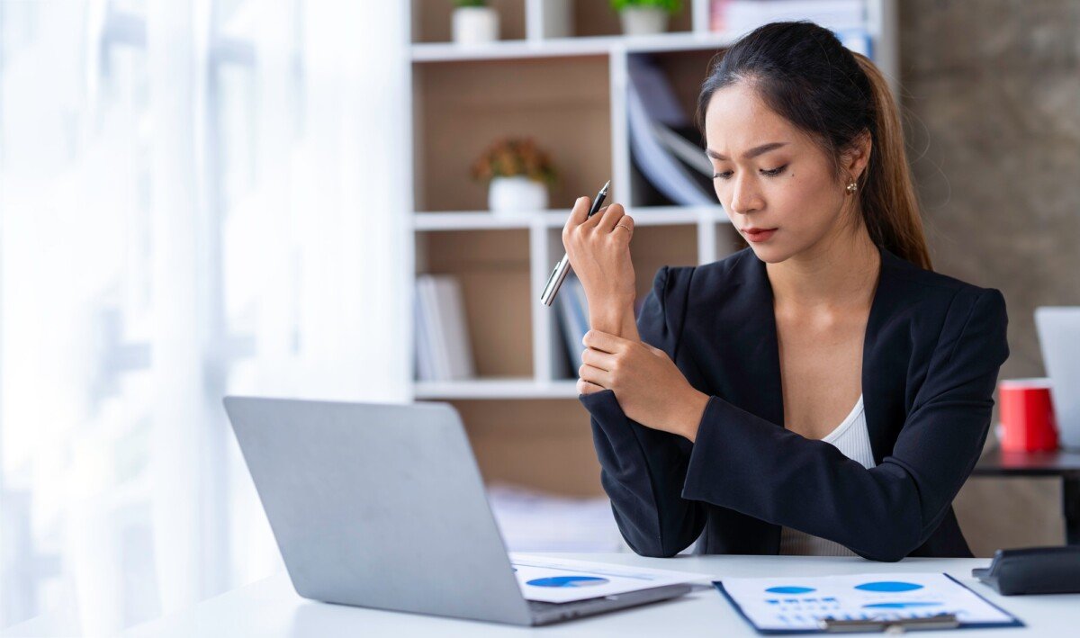Asian businesswoman with wrist pain in the office due to working in the wrong position for a long ti