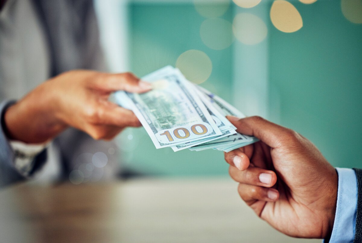 Hands, dollars and businessmen exchanging cash at a bank, making a purchase or deal. Closeup of mon.